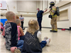 Firefighter geared up showing students