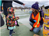 Child wearing multi-colored jacket at easter egg hunt talking with a volunteer
