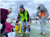 Volunteer handing out an Easter Egg, an elephant stands behind her