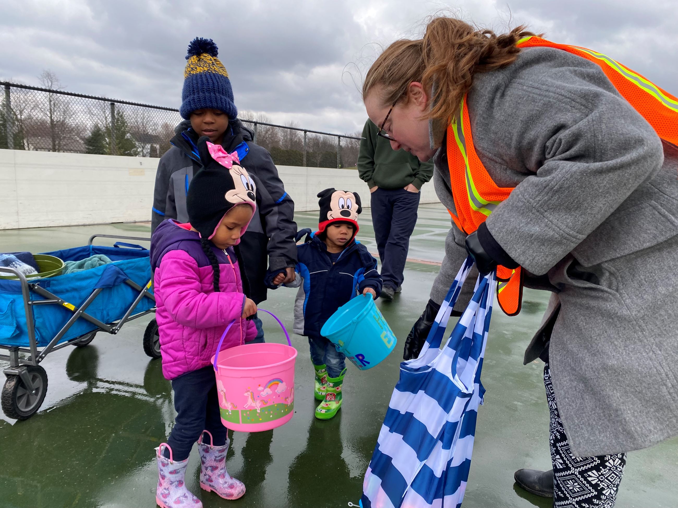 Volunteer helping three children with Easter Egg Hunt