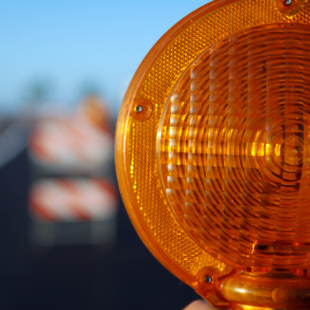 orange construction barrel with roadway in background